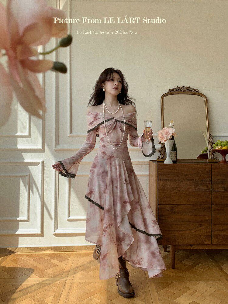 Model wearing a pink off-shoulder asymmetrical dress in a styled room
