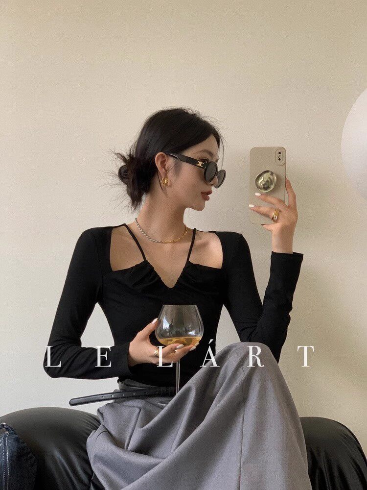 Black long-sleeve cutout top worn by a woman with a gray skirt