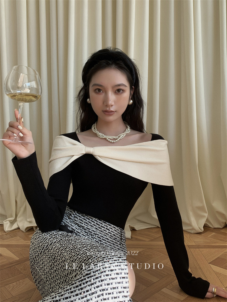 Woman wearing a black off-shoulder dress with a cream bow detail and patterned skirt