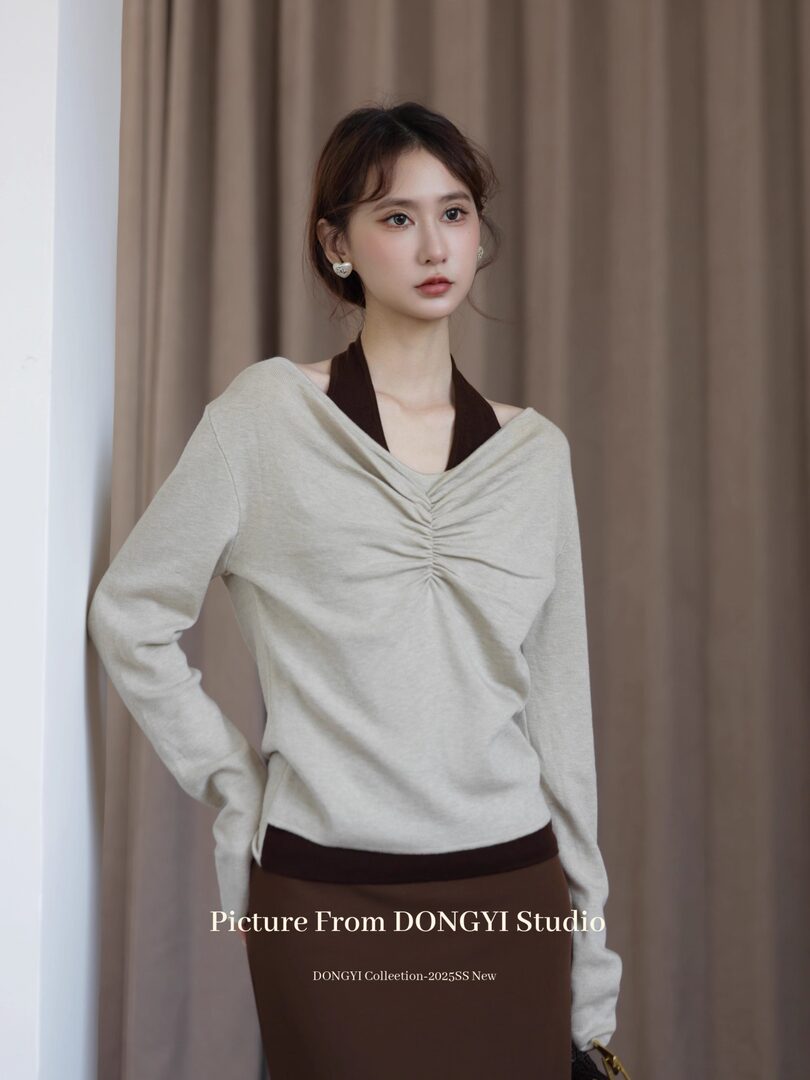 Model wearing a light gray ruched long-sleeve top with dark halter straps
