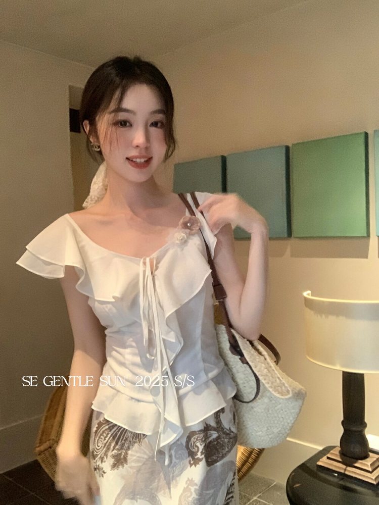 Woman modeling a white ruffled sleeveless top and patterned skirt