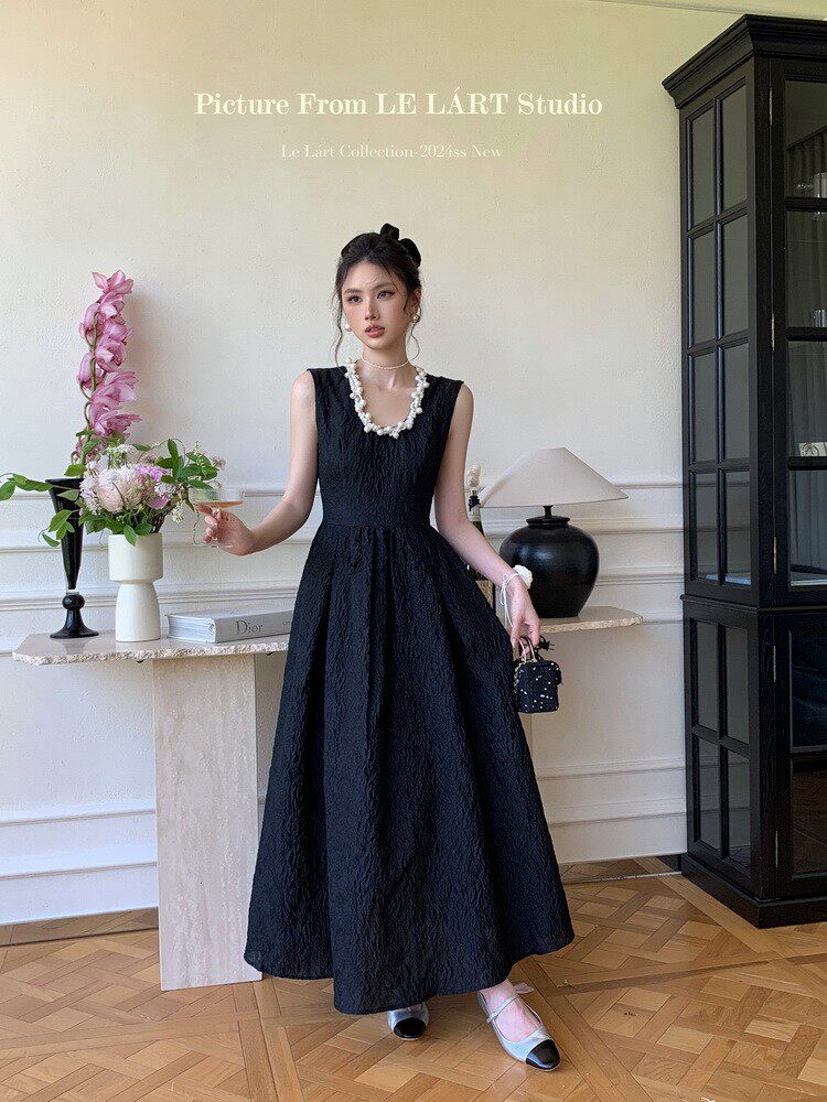 Woman wearing a black sleeveless full-length dress in a studio setting
