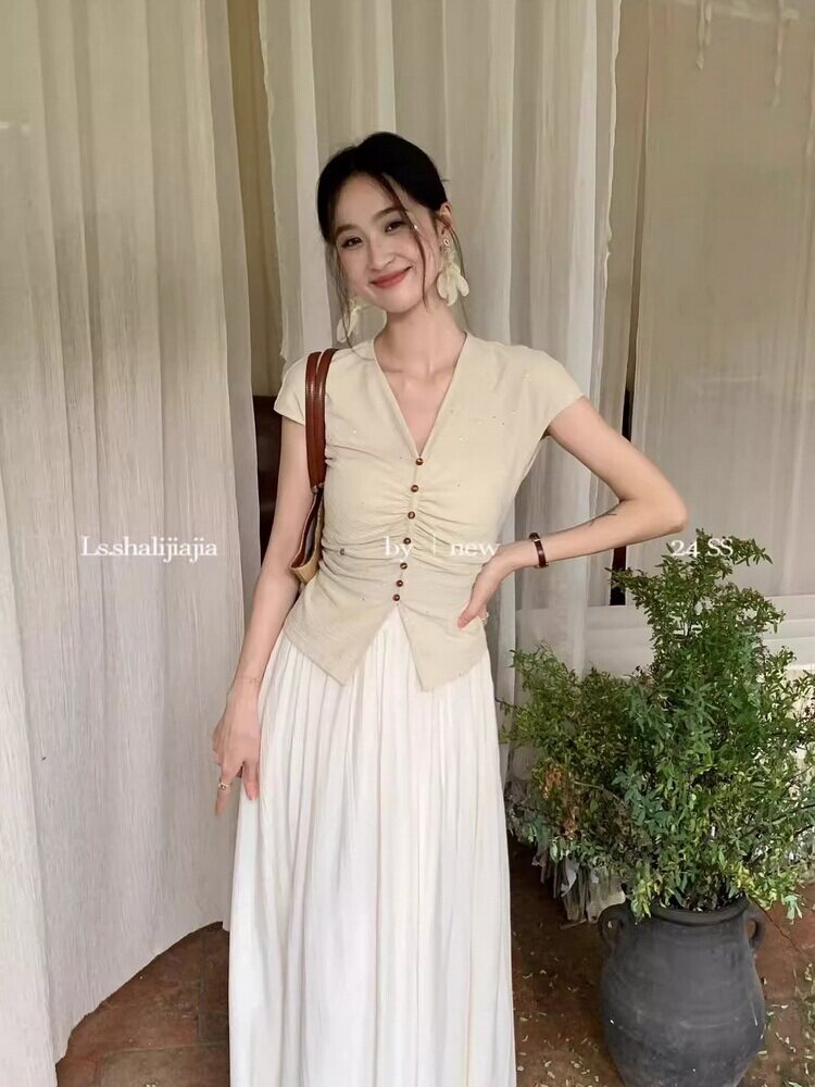 Woman wearing a beige button-front sleeveless top with a white pleated skirt