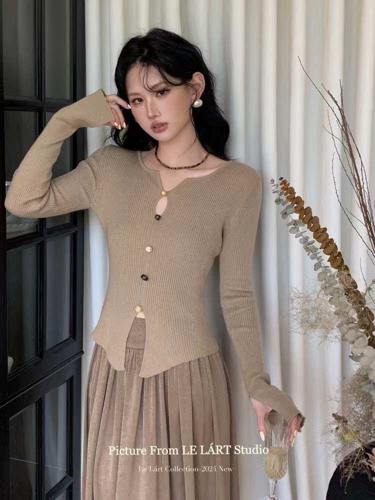 Beige ribbed knit long-sleeve top with matching pleated skirt worn by a model