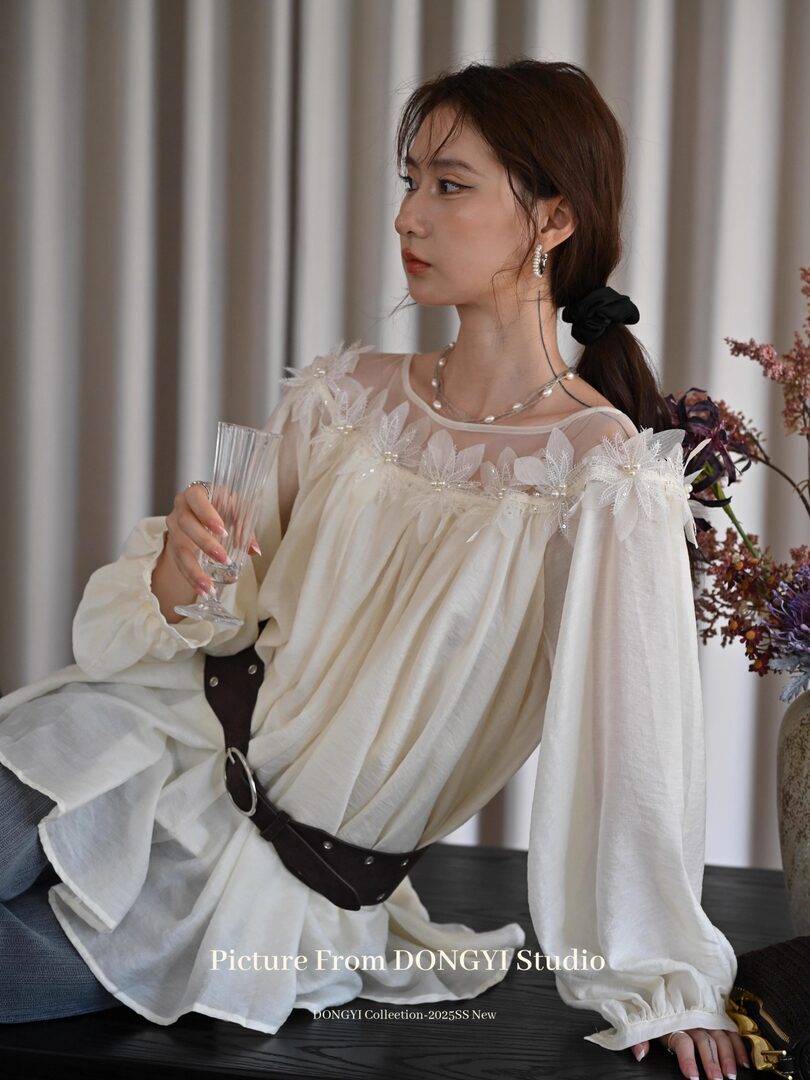 Woman wearing a sheer white floral-embellished blouse