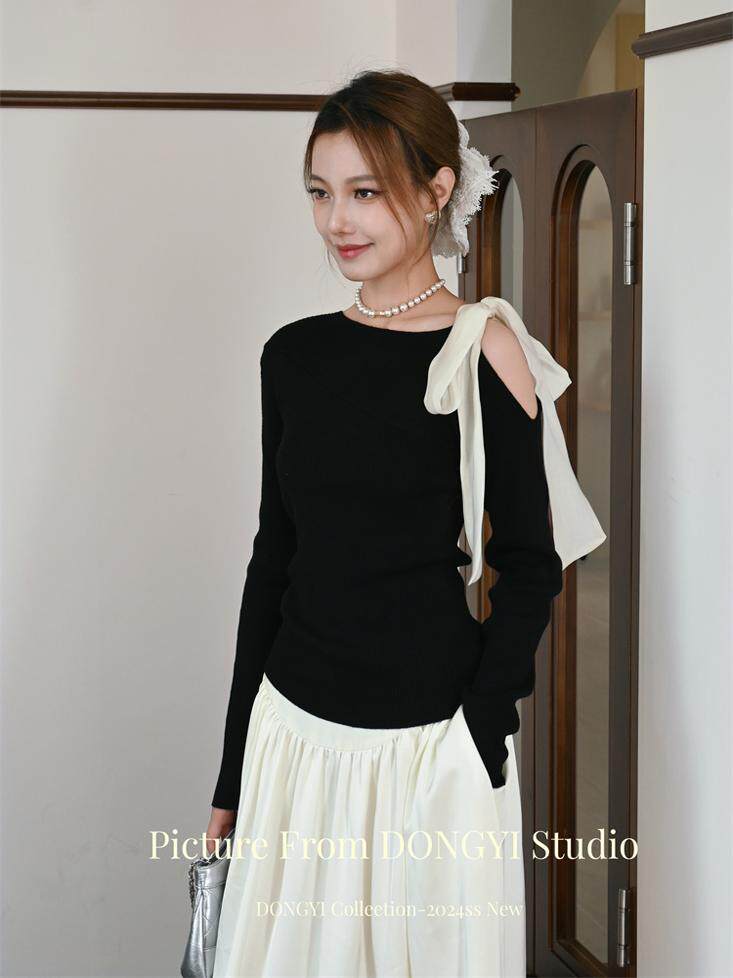 Woman modeling a black long-sleeve top with a white skirt