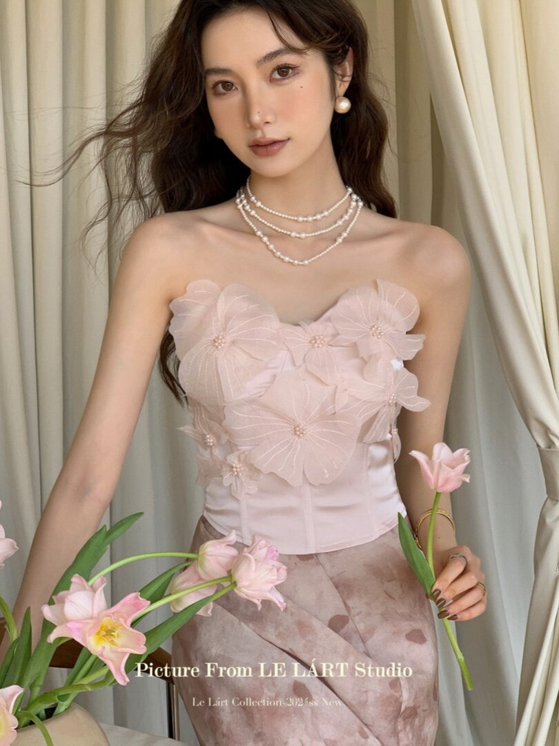 Model wearing a pale pink strapless floral dress with pearl jewelry