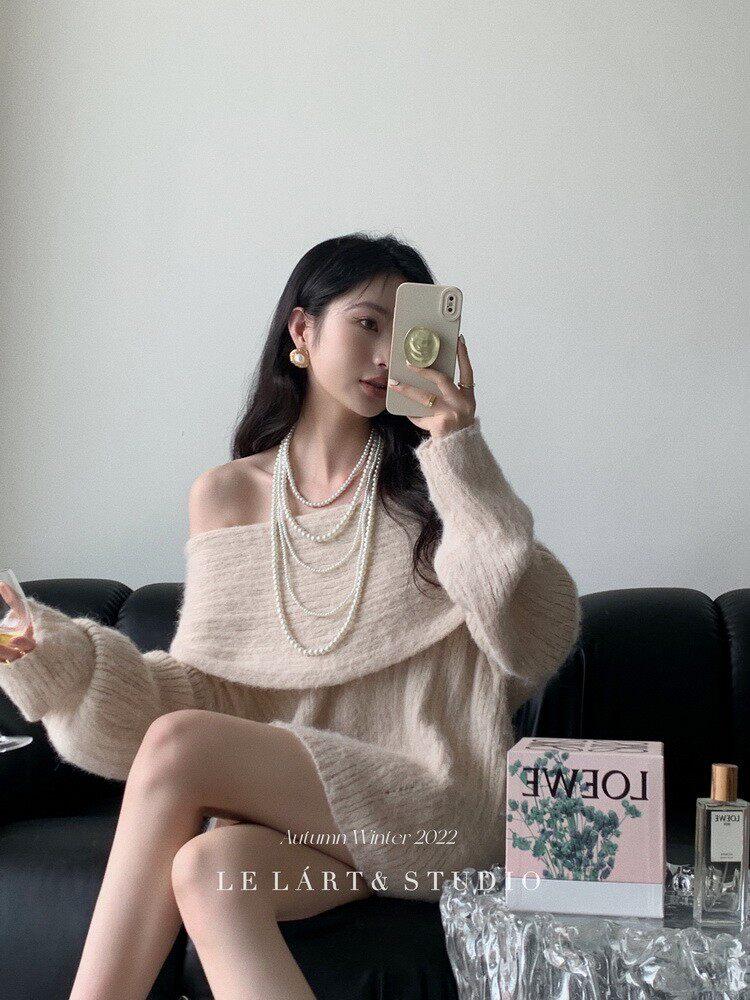 Woman wearing a cream off-shoulder fuzzy knit sweater in a styled indoor photo