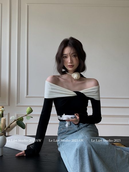 Woman wearing a black and white off-shoulder top with a denim skirt
