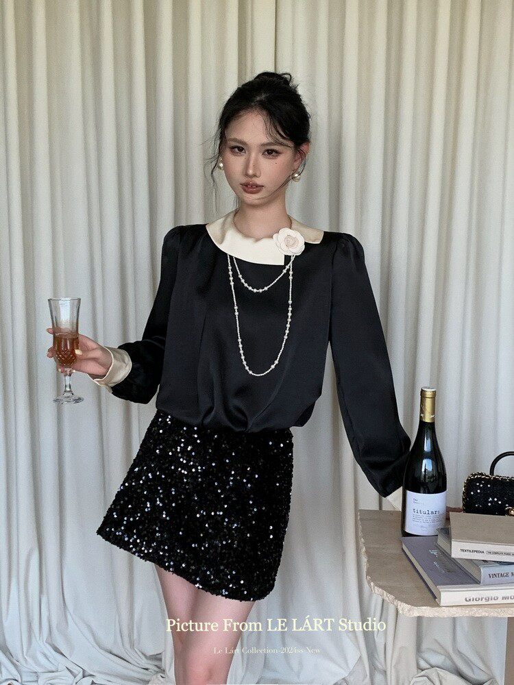 Model wearing a black long-sleeve blouse with a white collar and a black sequin mini skirt