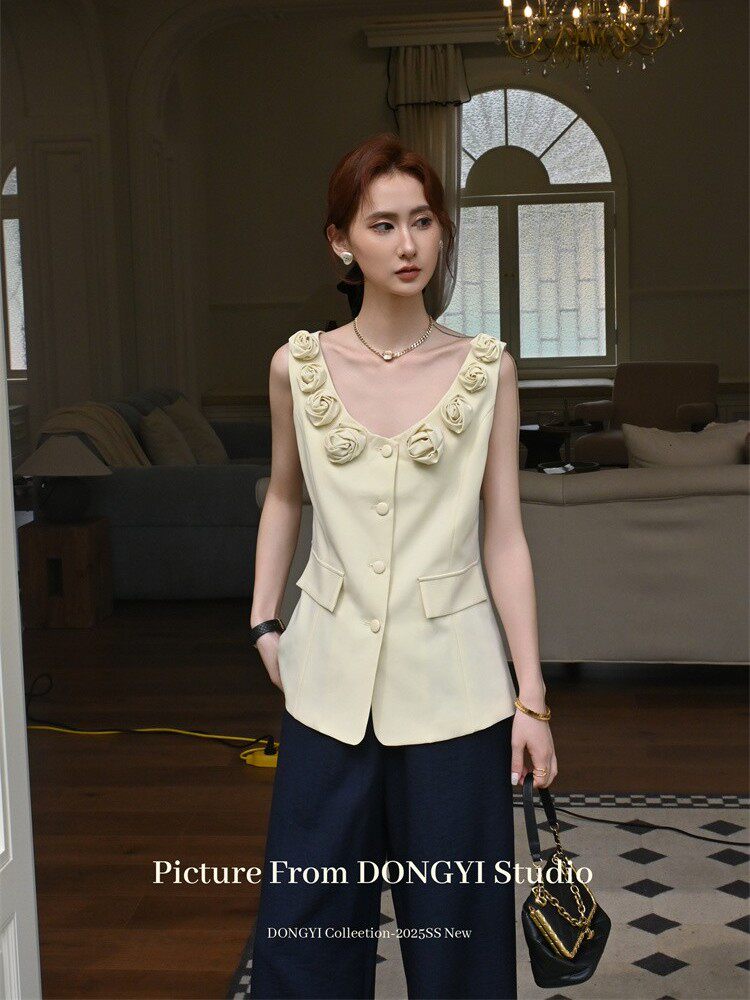 Model wearing a cream sleeveless floral-trim vest top with navy wide-leg pants