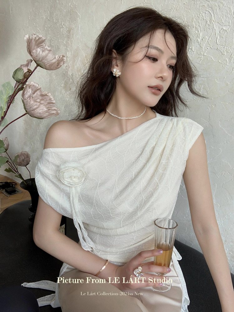 Woman wearing a white off-shoulder draped dress with floral detail