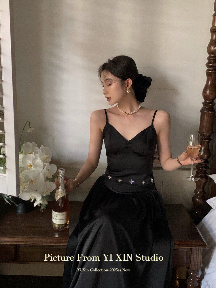 Black elegant dress worn by a woman, styled with pearl jewelry