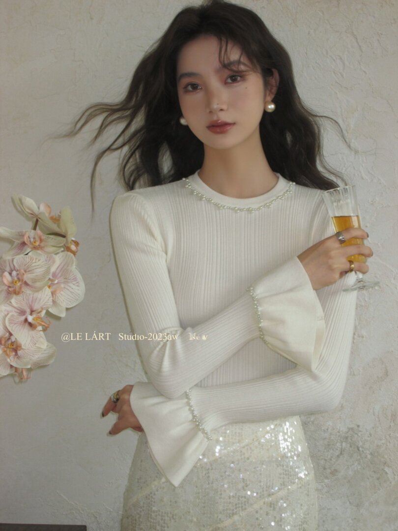 White ribbed long-sleeve top with flared cuffs worn by a model