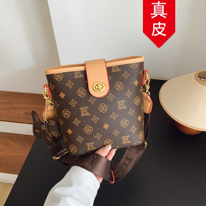 香港品牌高级感真皮水桶包包女2026新款时尚印花宽肩带单肩斜挎包