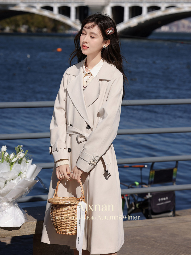 Woman wearing a beige trench coat by the water