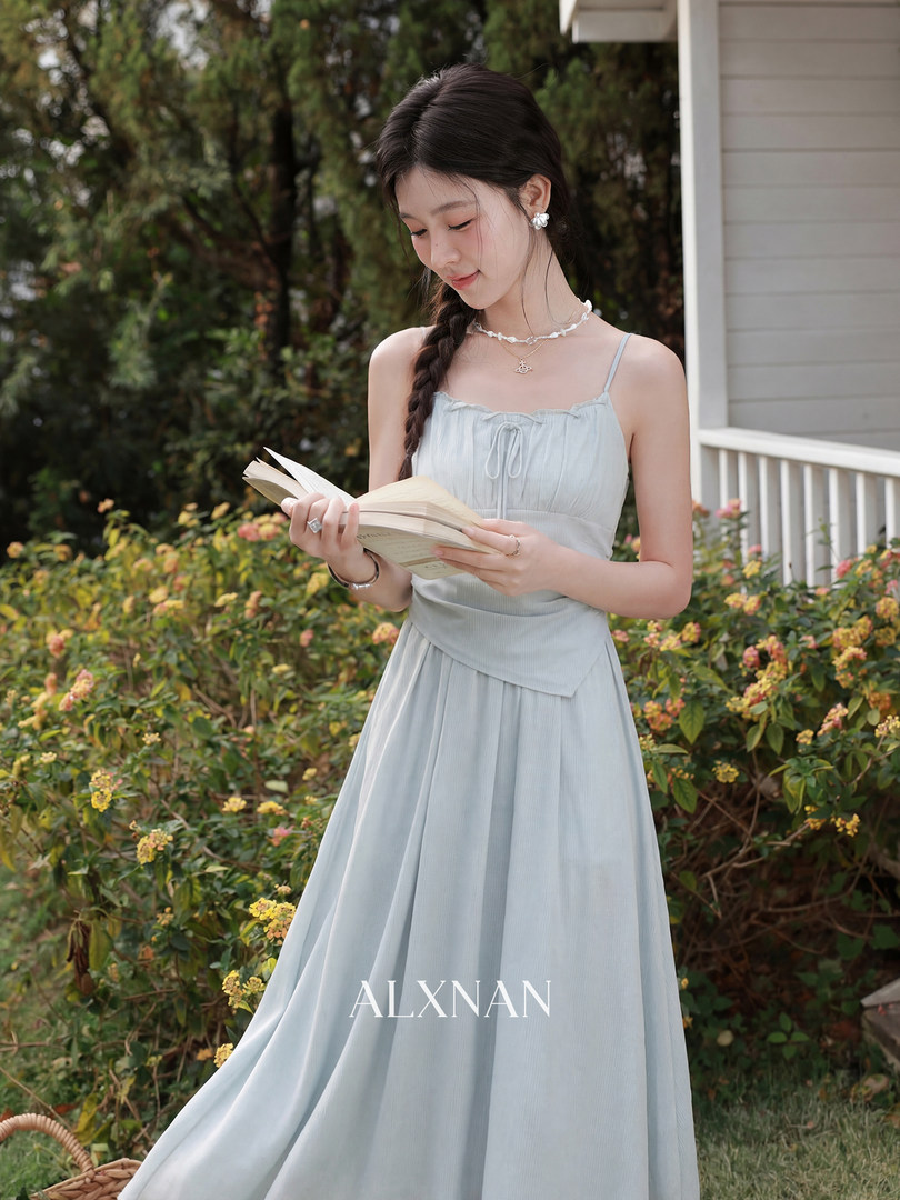 Model wearing a light blue flowy spaghetti-strap dress outdoors