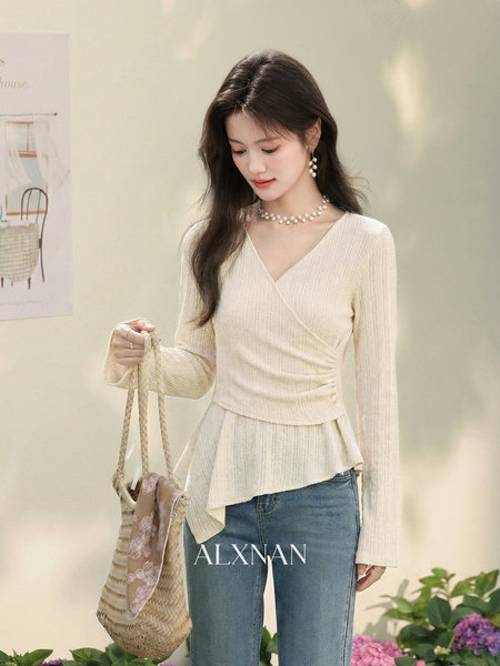 Model wearing a cream wrap knit top with blue jeans and a woven bag