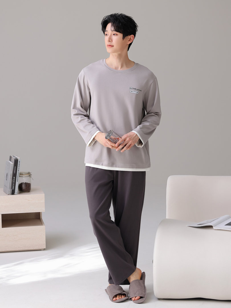 Male model wearing a light gray long-sleeve top with dark lounge pants and slippers