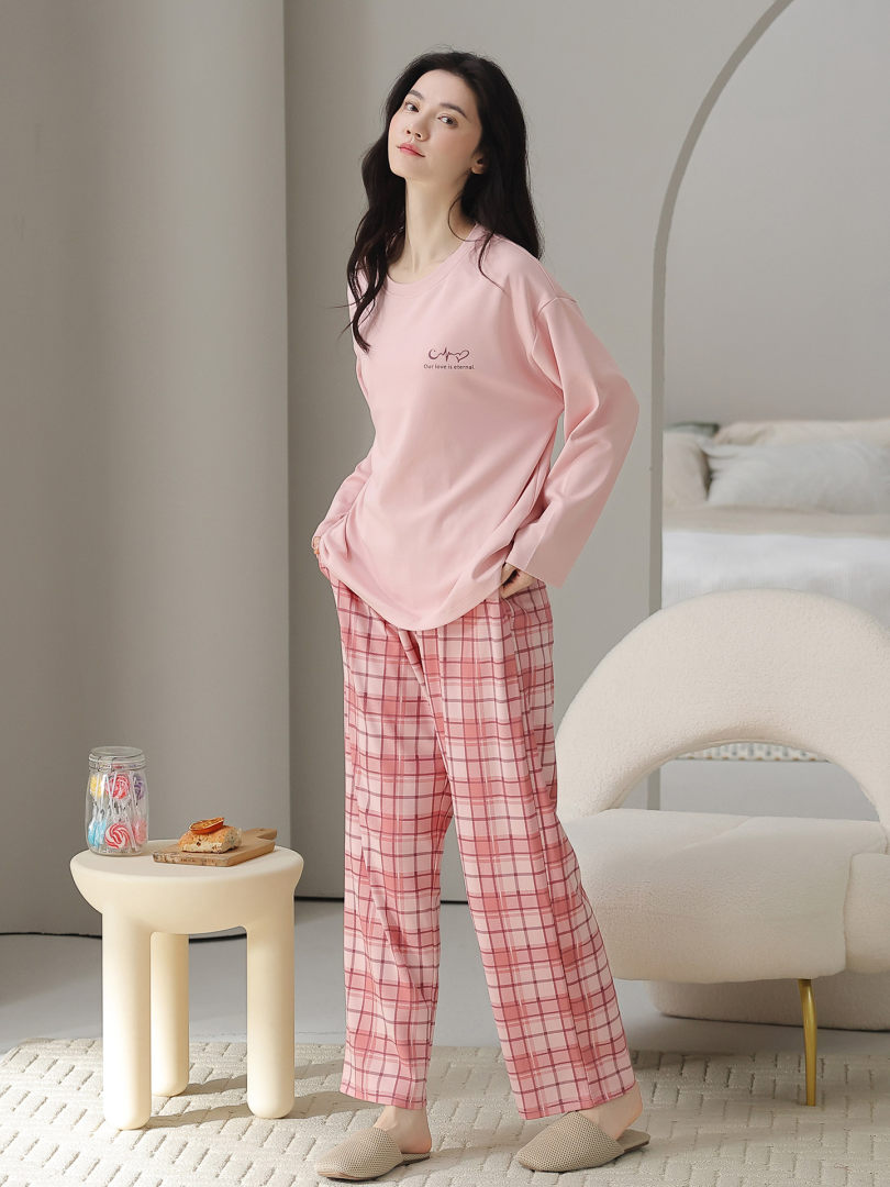 Pink long-sleeve pajama set with plaid pants worn by a model