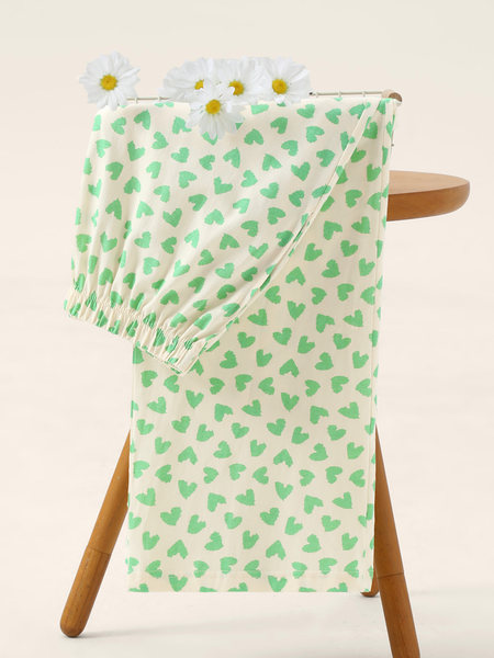 Cream elastic-waist garment with green heart print displayed on a chair