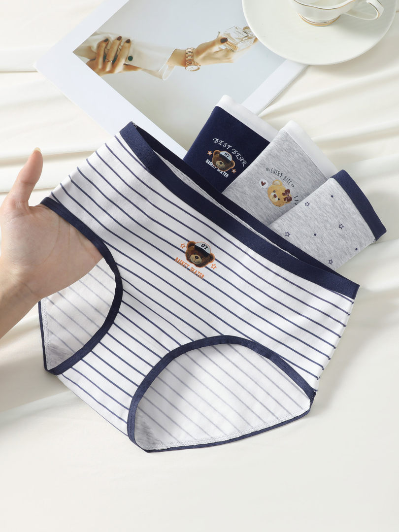 Three pairs of striped cotton underwear briefs with cute bear prints laid out on a white surface