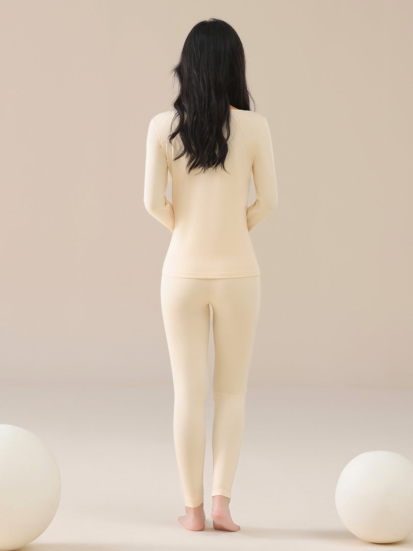 Woman wearing a cream long-sleeve top and matching leggings on a plain background