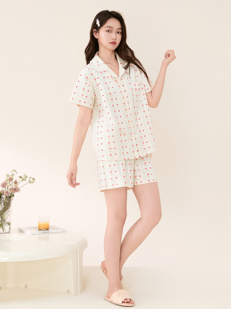 Female model wearing a cream heart-print pajama set with shorts and short-sleeve top