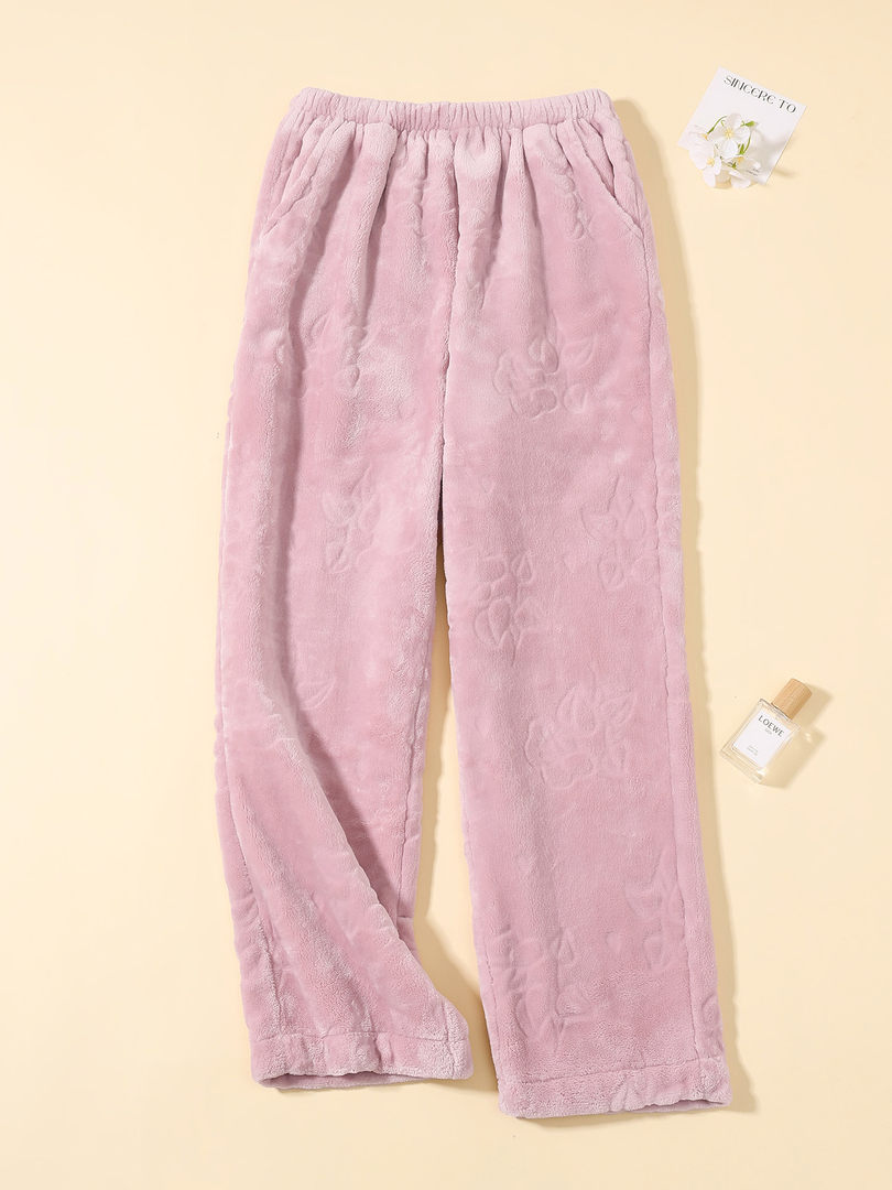 Pink plush fleece pants laid flat on a beige background