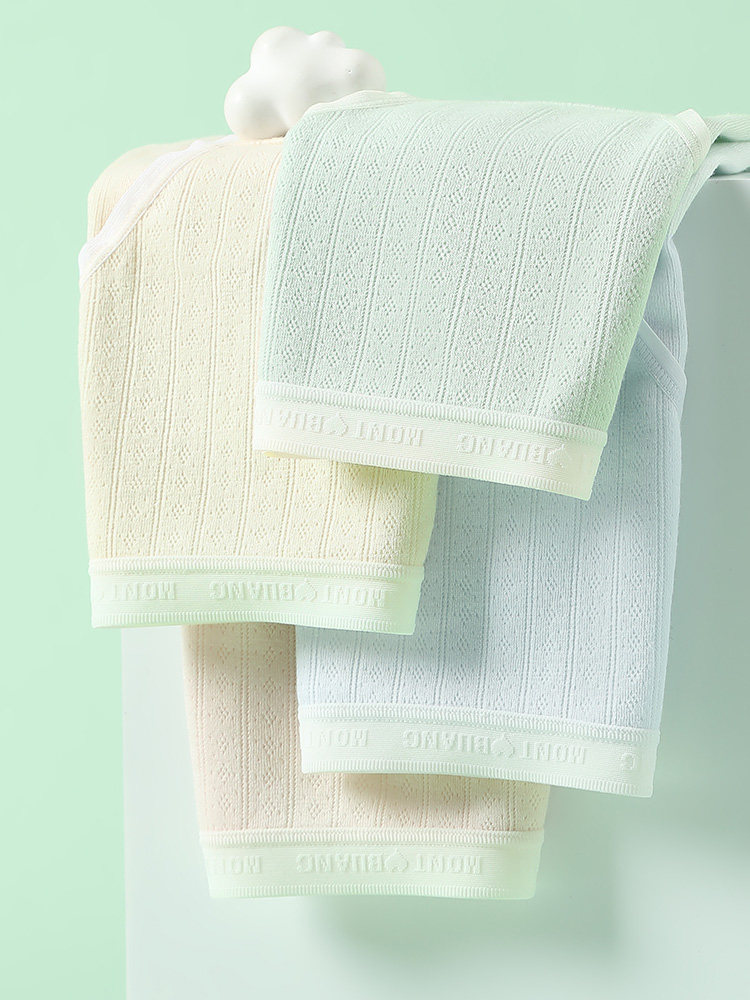 Folded pastel waffle-knit towels on a mint background