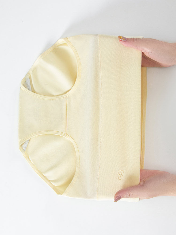 Light yellow sleeveless shapewear or tank-style undergarment held in hands