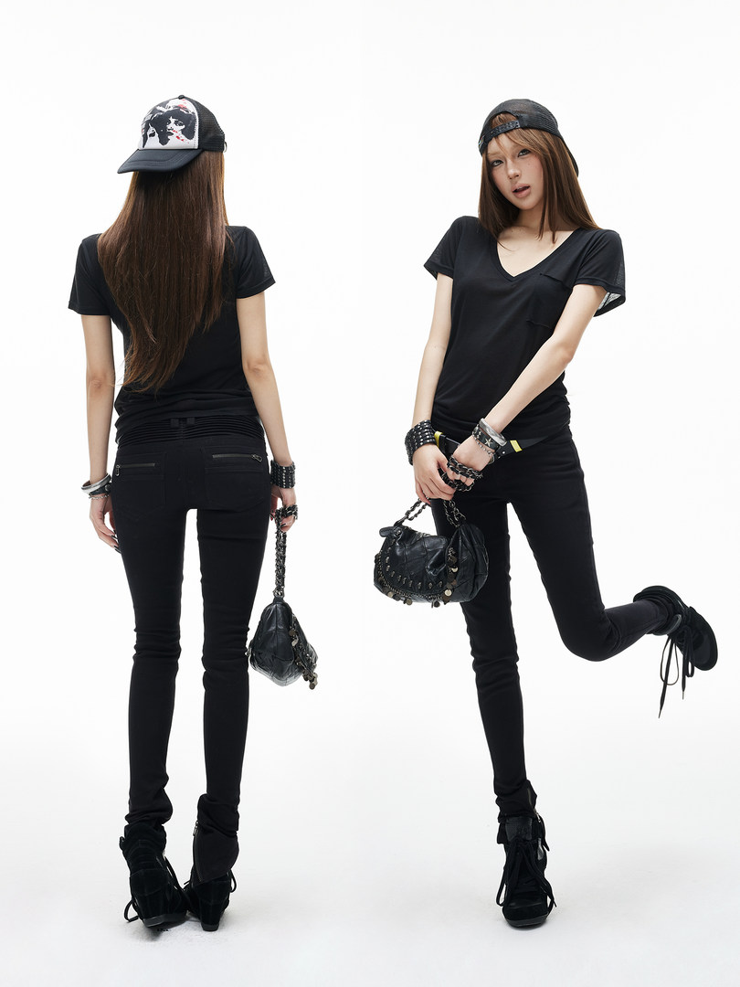Model wearing a black casual streetwear outfit with cap, tee, skinny jeans, boots, and handbag