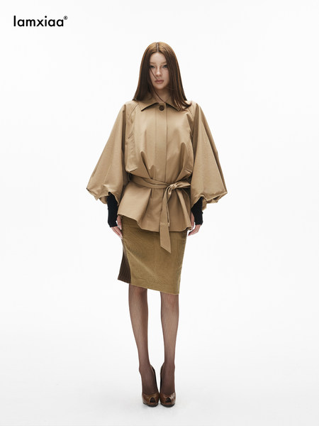Model wearing a beige belted blouse with a matching skirt on a white background