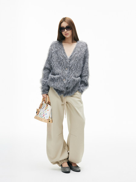 Fashion model wearing a fuzzy gray cardigan with beige pants and a designer handbag