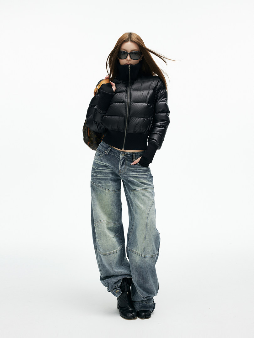 Model wearing a black puffer jacket with wide-leg blue jeans and black boots