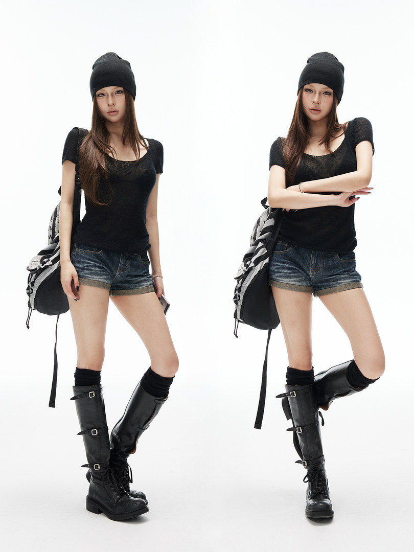 Fashion model wearing a black top, denim shorts, beanie, and black knee-high boots