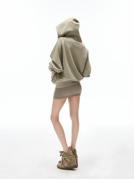 Model wearing an oversized beige hoodie with a mini skirt and high-top sneakers on a white background