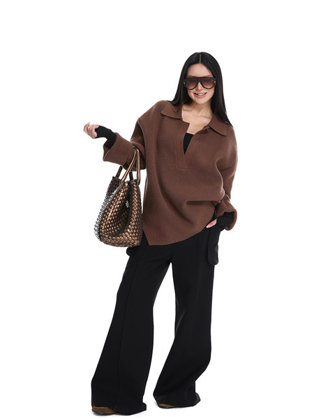 Woman wearing a brown oversized sweater with black wide-leg pants and a woven handbag