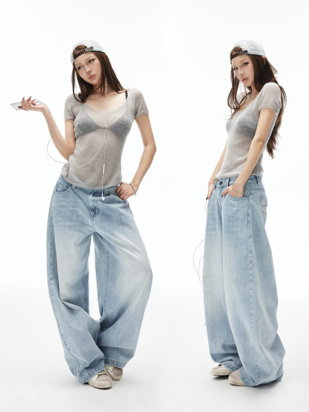 Model wearing light wash wide-leg jeans and a sheer knit top on a white background