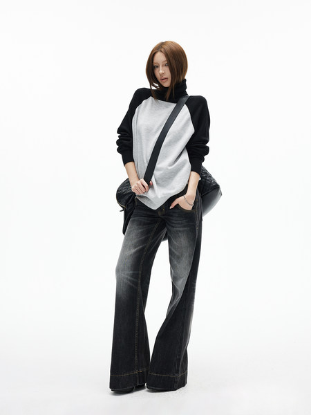Model wearing a black-and-white turtleneck top with wide-leg dark jeans and a crossbody bag