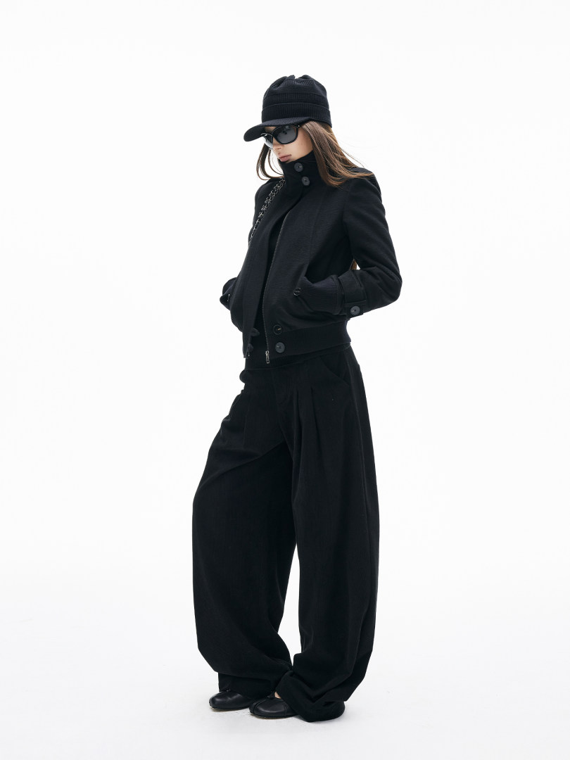 Model wearing a black fashion outfit with hat, sunglasses, jacket, and wide-leg pants