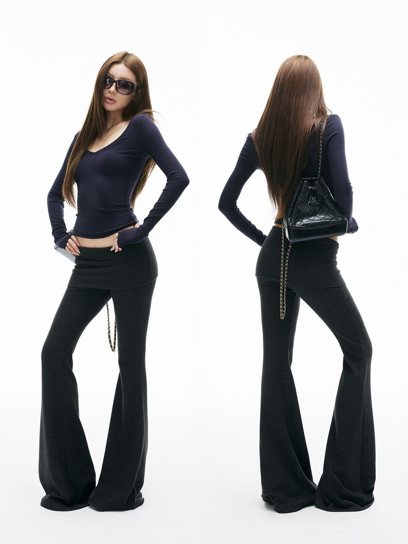 Model wearing a fitted dark top with black flared pants and a black quilted shoulder bag