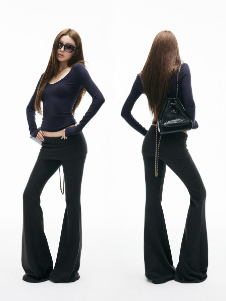 Model wearing a fitted dark top with black flared pants and a black quilted shoulder bag