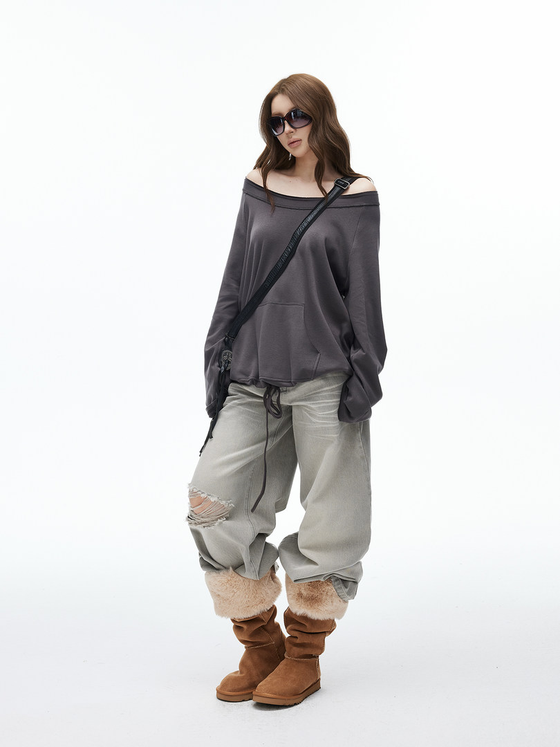 Model wearing an off-shoulder oversized top with loose pants and fur-trimmed boots