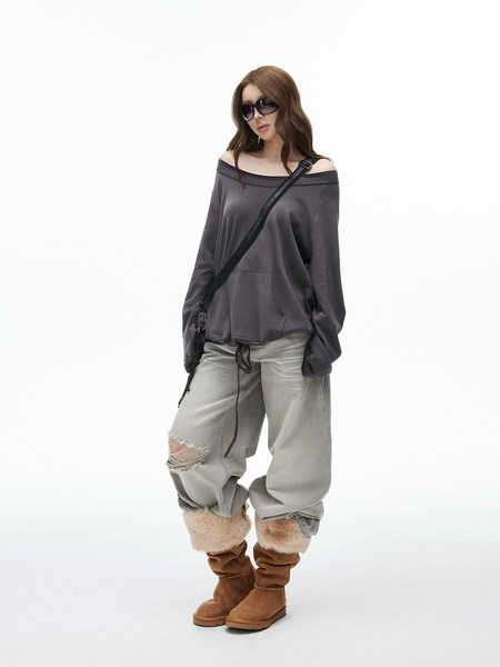 Model wearing an off-shoulder oversized top with loose pants and fur-trimmed boots