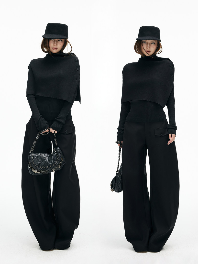 Model wearing an all-black fashion outfit with wide-leg pants, turtleneck top, cap, and chain handbag