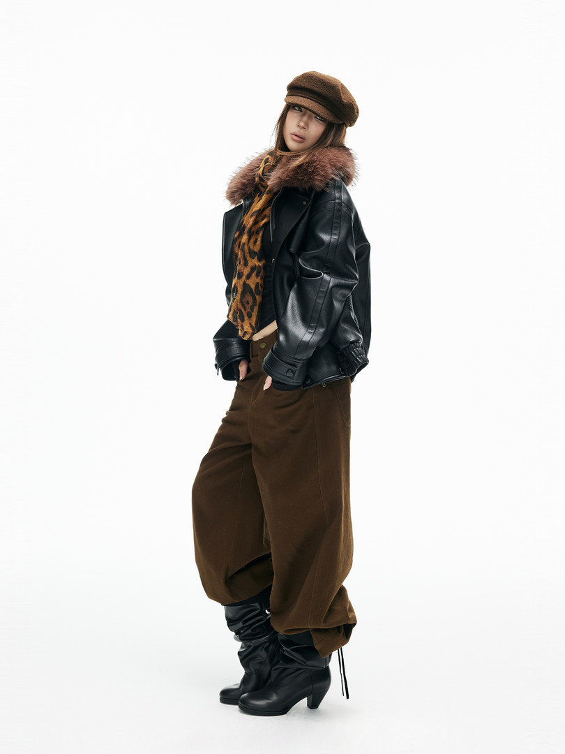 Fashion model wearing a black leather jacket, brown pants, and black boots