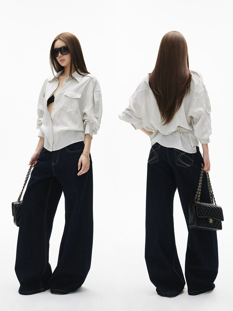 Model wearing a white striped button-up shirt with wide-leg black jeans and a black chain-strap handbag