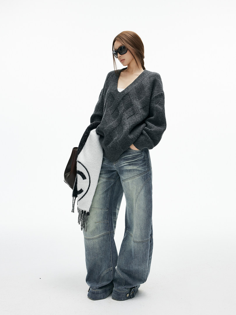 Model wearing an oversized dark knit sweater with wide-leg faded jeans