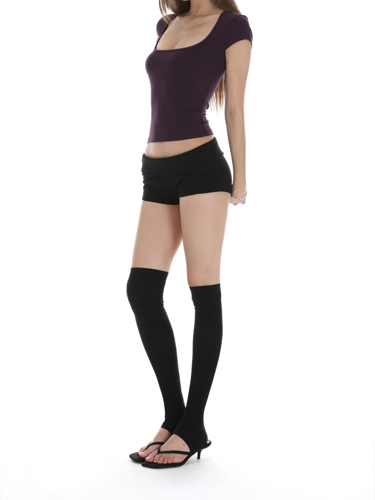 Woman wearing a purple fitted top with black shorts and thigh-high socks